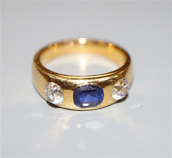 A yellow metal (stamped 22) gypsy set sapphire and diamond three stone ring,
